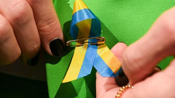 Ein Gast der Berliner Fashion-Week steckt sich aus Solidarität eine Schleife mit der ukrainischen Flagge an.
