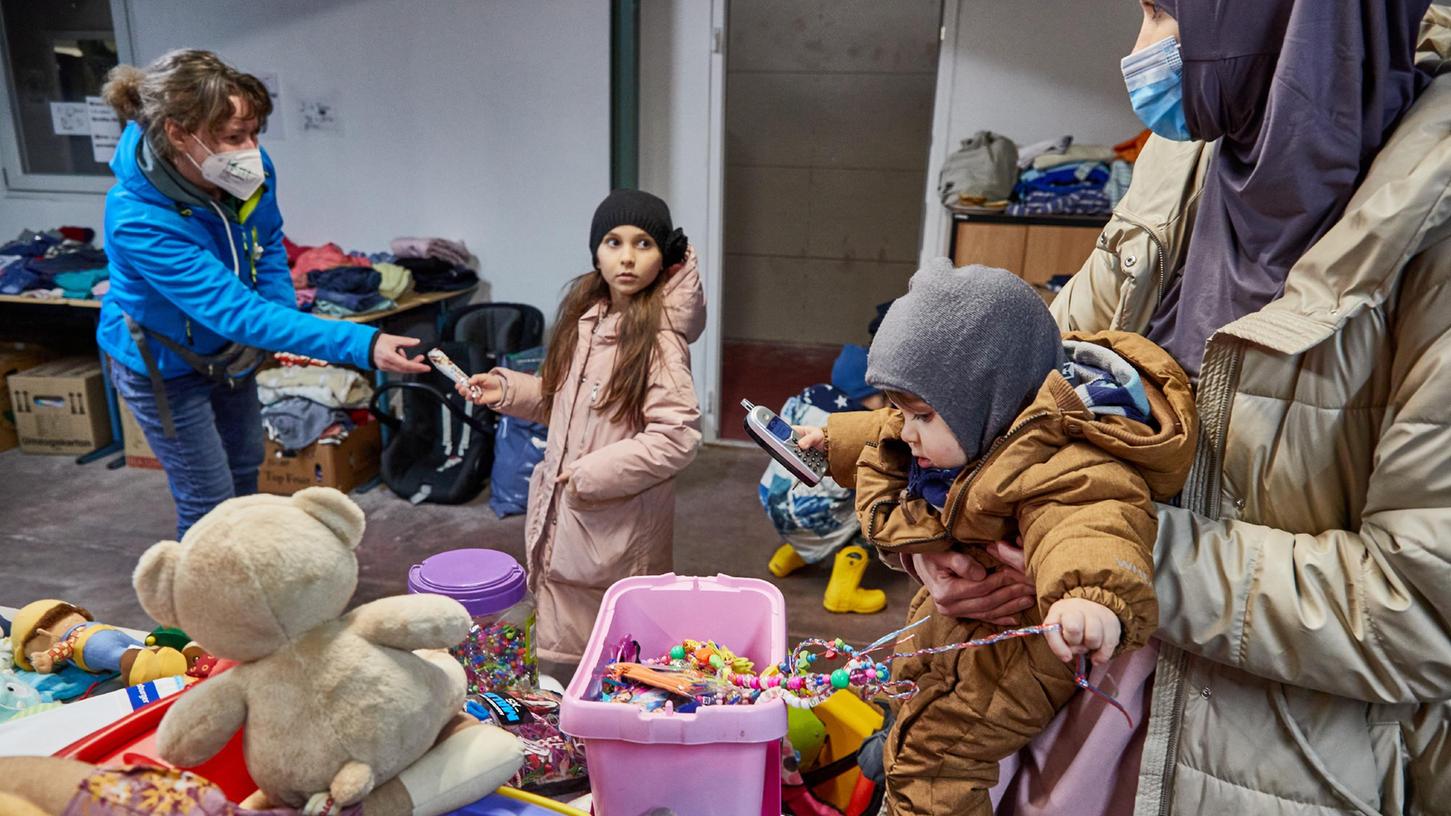 Eine ehrenamtliche Helferin versorgt eine ukrainische Flüchtlingsfamilie in einer Kleiderkammer des Arbeiter-Samariter-Bundes in Hamburg.