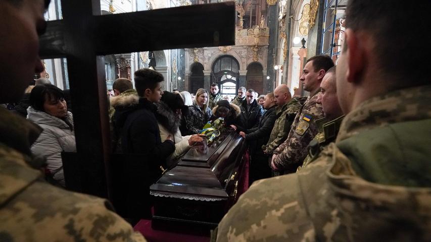 Töten für den Frieden? In Lwiw, Ukraine, stehen am 15. März ukrainische Soldaten während einer Trauerfeier in einer Kirche mit weiteren Personen um den Sarg eines ukrainischen Militärangehörigen, der im Einsatz ums Leben kam.
