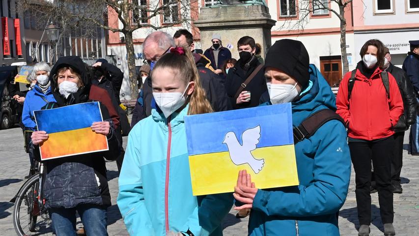 Die ukrainische Fahne mit Friedenstaube:  Demonstranten beteiligen sich an der ersten Kundgebung, zu der die Erlanger Christen für den Frieden aufgerufen hatten; unterstützt wurden sie dabei von fast allen Fraktionen des Erlanger Stadtrats.