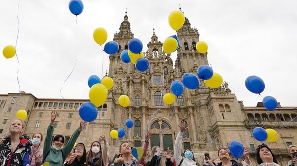 Spanien, Santiago De Compostela, A Coruña: Menschen lassen auf dem Obradoiro-Platz Luftballons in den Farben der ukrainischen Flagge in die Luft steigen, um das Ende des Krieges in der Ukraine zu fordern. Die Veranstaltung, an der auch ukrainische Flüchtlinge teilnahmen, wurde von einem Forschungszentrum der Universität Santiago de Compostela organisiert.