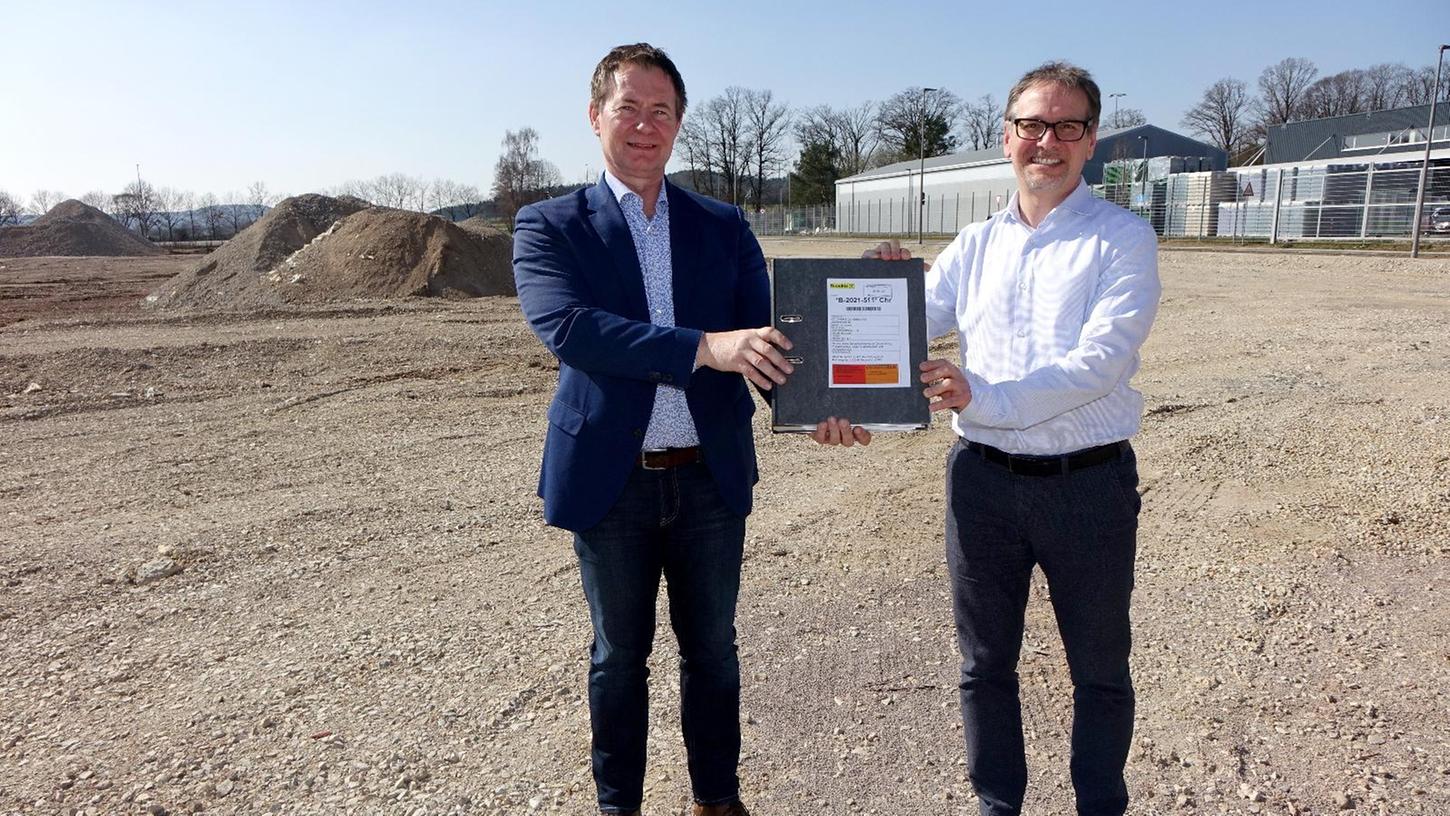 Oberbürgermeister Thomas Thumann überreicht die Baugenehmigung an Björn Poy (rechts) auf dem Gelände des künftigen Dehner-Marktes.