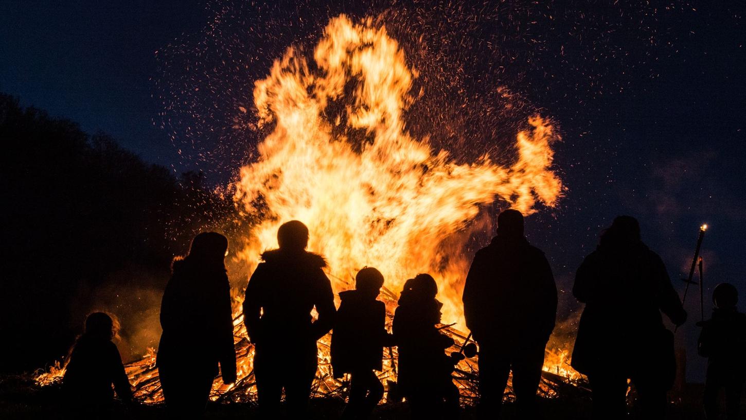 Menschen stehen an einem traditionellen Osterfeuer.