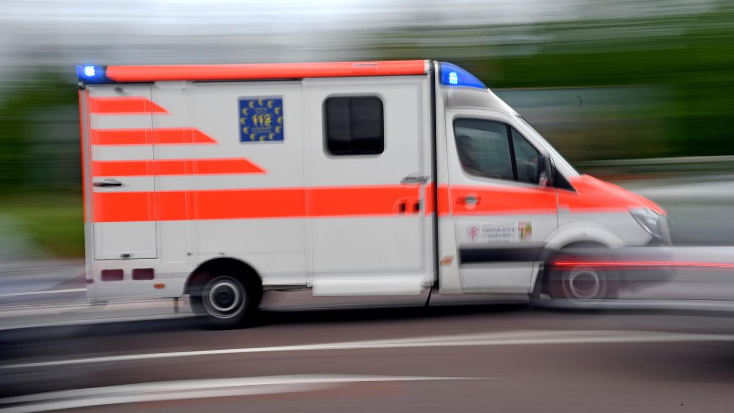 Ein Krankenwagen fährt mit Blaulicht auf einer Straße. Ein Krankenwagen fährt mit Blaulicht auf einer Straße.