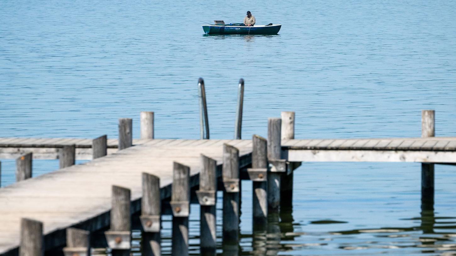 Ein Mann auf seinem Ruderboot angelt auf dem Ammersee in der Bucht von Herrsching. Mitte der Woche könnten es in manchen Orten Bayerns an die 30 Grad warm werden. Ein Mann auf seinem Ruderboot angelt auf dem Ammersee in der Bucht von Herrsching. Mitte der Woche könnten es in manchen Orten Bayerns an die 30 Grad warm werden.