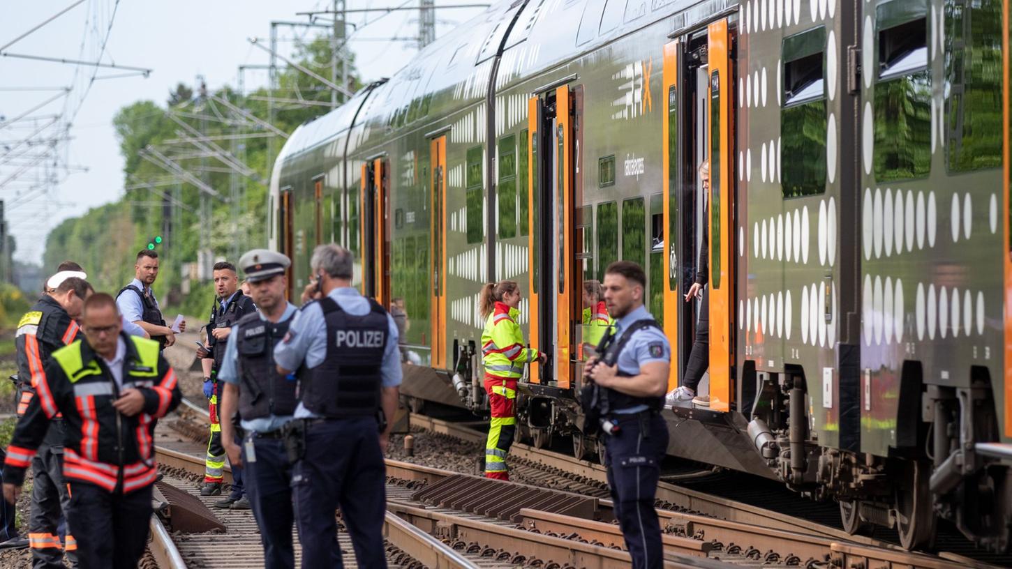 Polizisten stehen vor der Regionalbahn, in der sich die Attacke ereignete.