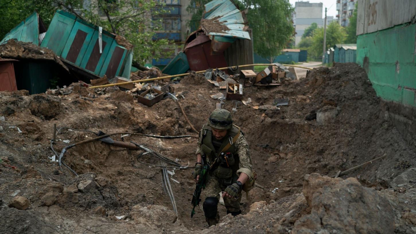 Ein Uniformierter inspiziert einen Krater nach einem Luftangriff der russischen Streitkräfte in der Region Luhansk. Ein Uniformierter inspiziert einen Krater nach einem Luftangriff der russischen Streitkräfte in der Region Luhansk.