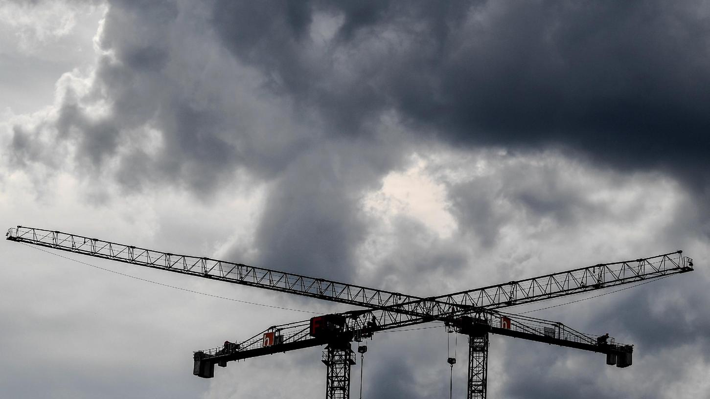 Baukräne vor dunklen Wolken. Mit Sorge sehen die mittelfränkischen Unternehmen laut IHK auf die nächsten Monate.