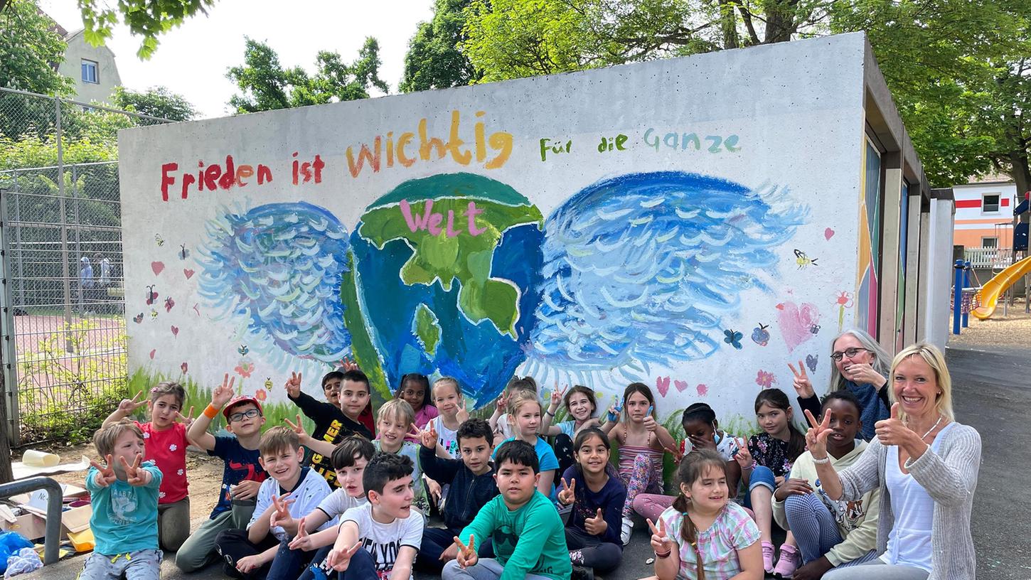 Die Klasse 2e der Sperberschule hat im Pausenhof mit der Künstlerin Patrizia Arrigo-Daumenlang (rechts hinten) ein Kunstwerk zum Thema Frieden gestaltet. Vorne rechts Klassenlehrerin Susanne Pechstein.
