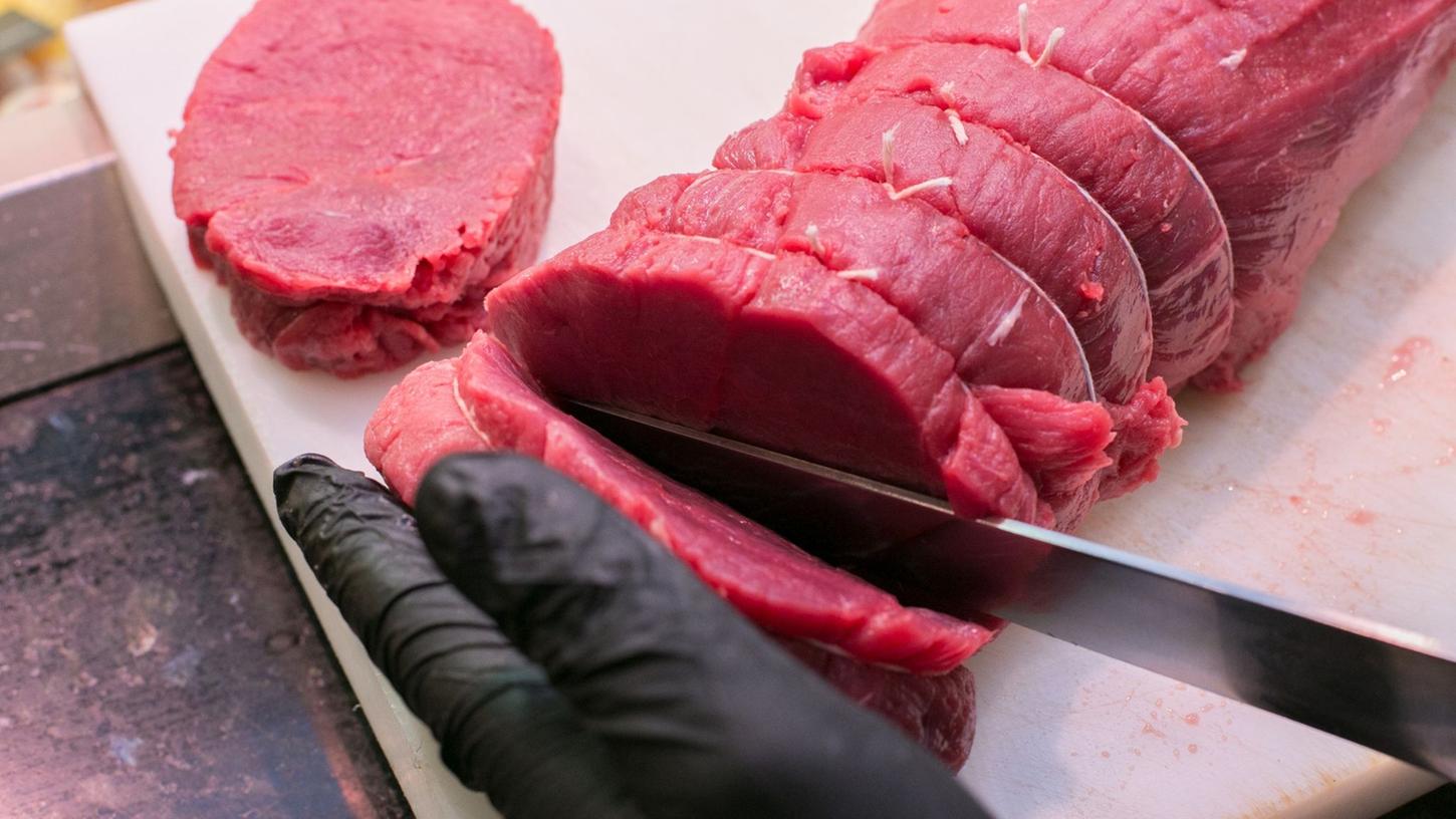 Ein Fleischer zeigt, wie er Steaks von einem Stück Rind quer zur Faser schneidet. Ein Fleischer zeigt, wie er Steaks von einem Stück Rind quer zur Faser schneidet.