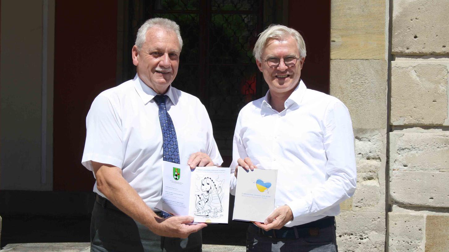 Bürgermeister Klaus Meier nahm dankbar das "Beschäftigungsbuch für ukrainische Flüchtlingskinder" entgegen, das Roland Keppler (rechts) übergab.
