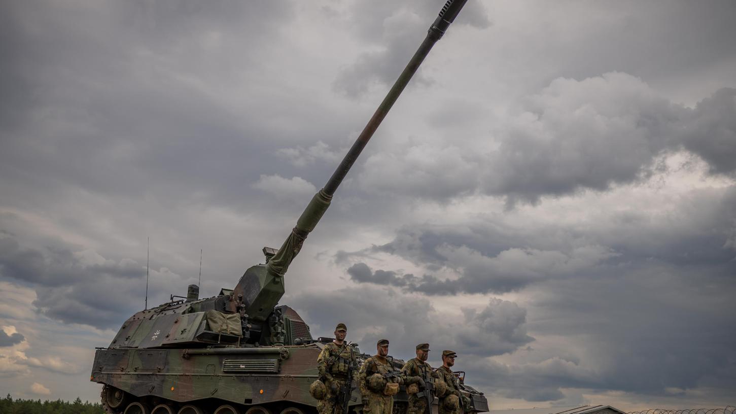 Soldaten stehen vor einem gepanzerten, selbstfahrenden Artilleriegeschütz vom Typ Panzerhaubitze 2000 der Bundeswehr. Ukrainische Soldaten werden derzeit an dieser Waffe ausgebildet.
