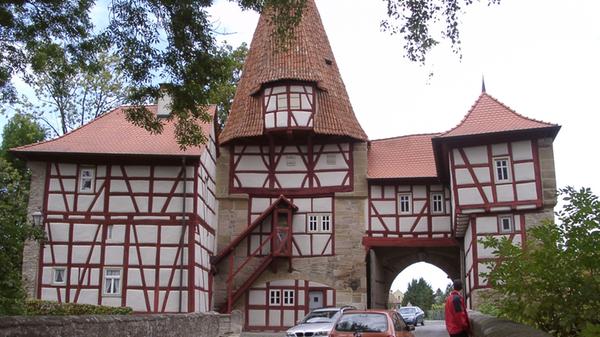 Das Rödelseer Tor ist das bekannteste und älteste von den drei noch erhaltenen Stadttoren in Iphofen. Mit seinem originellen hohlziegelbedachtem Turm, dem schmucken Fachwerk und dem Torhaus wurde es zum Motiv unzähliger Maler und Fotografen und zugleich zum Wahrzeichen der Stadt. Bemerkenswert ist das „Schlupflöchlein“ in den noch heute eingehängten Torflügeln. Es konnte geöffnet werden, wenn ein verspäteter Ankömmling um Einlass bat.