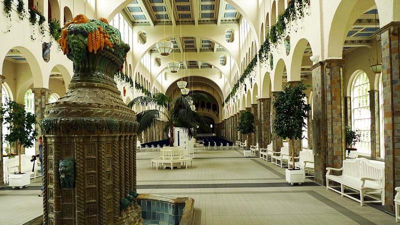 Die Wandelhalle wurde zwischen 1910 und 1911 nach Plänen des Architekten Max Littmann errichtet. Sie ist 90 Meter lang und gilt als größte Wandelhalle Europas. Mit ihrem durch Säulenreihen in drei Längsschiffe geteilten Innenraum ist sie wie eine Basilika angelegt. Die durchgängige Konstruktion aus Stahlbeton galt zur Bauzeit als ebenso innovativ wie die nach außen in den Kurgarten drehbare Konzertmuschel. In der Brunnenhalle schenken Brunnefrauen mehrmals am Tag vier der sieben Bad Kissinger Heilwässer aus. Während des bewussten Trinkens wandeln die Gäste durch die große Halle.