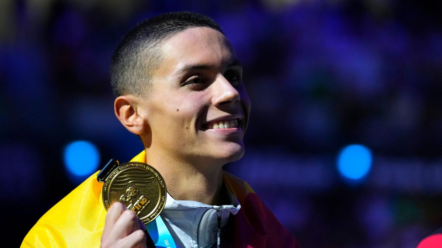 Der Rumäne David Popovici hält seine Goldmedaille bei der Siegerehrung in der Hand. Der Rumäne David Popovici hält seine Goldmedaille bei der Siegerehrung in der Hand.