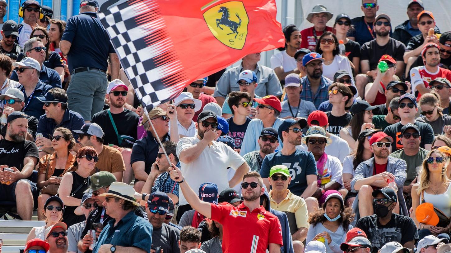 Ein Fan schwenkt eine Ferrari-Flagge auf einer Tribüne.