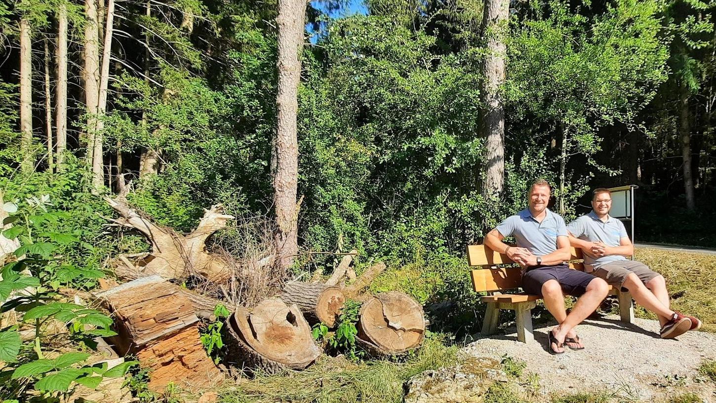 Bernhard Ziegler (l.) und Christian Schindler ruhen sich auf der von der JAU gespendeten Sitzbank aus. Daneben wurde ökologisch wertvolles Totholz aufgeschichtet.