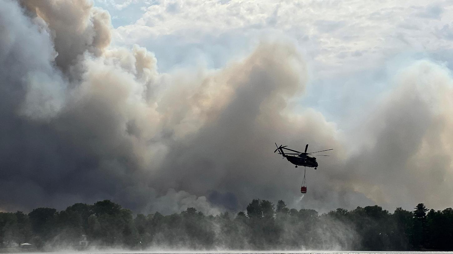 Ein Löschhubschrauber tankt Wasser an einem See: Bayern setzt bei der Bekämpfung von Waldbränden nicht auf Löschflugzeuge sondern auf die Unterstützung durch Hubschrauber.