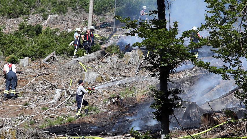 Einsatzkräfte der Feuerwehr löschen am Montag, 18. Juli, einen Waldbrand in der Nähe des unterfränkischen Mespelbrunn. Das Feuer war auf etwa 800 Quadratmetern ausgebrochen.