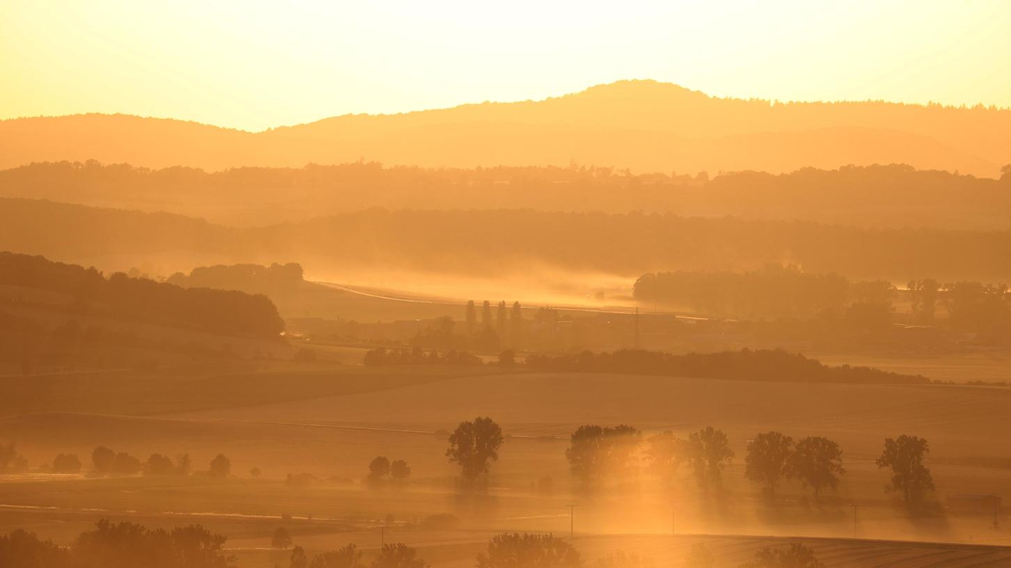 Trockenes Westmittelfranken: Von Traktoren aufgewirbelter Staub wird von der tiefstehenden Sonne bei Uffenheim beleuchtet. 