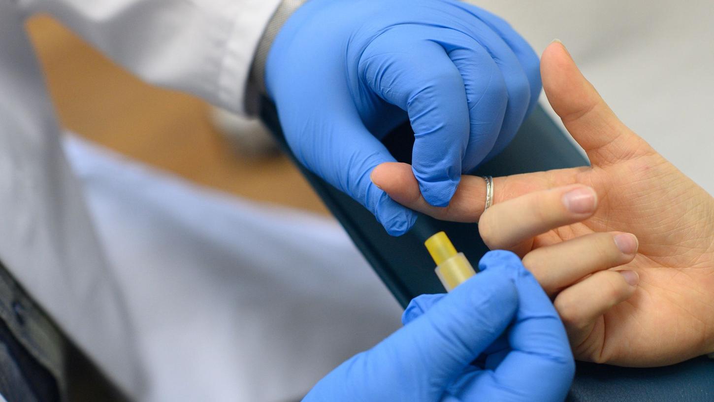 Ein Mitarbeiter der Aids-Hilfe Sachsen-Anhalt demonstriert im Labor die Blutentnahme für einen HIV-Test.