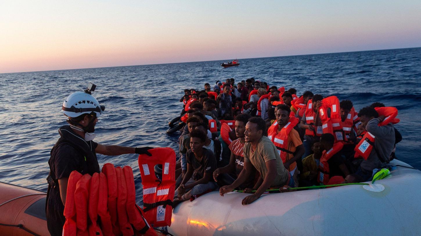 Die Besatzung der Sea-Watch 3 verteilt Rettungswesten an Menschen in einem Schlauchboot, mit dem sie versuchten nach Europa zu gelangen. Die Besatzung der Sea-Watch 3 verteilt Rettungswesten an Menschen in einem Schlauchboot, mit dem sie versuchten nach Europa zu gelangen.