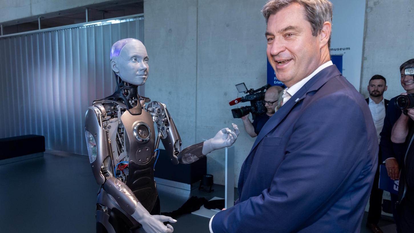 Willkommen, Herr Ministerpräsident! Markus Söder wird von einem humanoiden Roboter im Zukunftsmuseum begrüßt.
