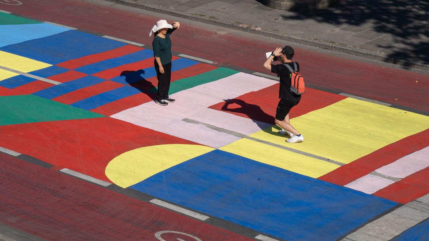 Touristen nutzen die bunt bemalte Fahrbahn am Mainkai für ein Erinnerungsfoto. Touristen nutzen die bunt bemalte Fahrbahn am Mainkai für ein Erinnerungsfoto.