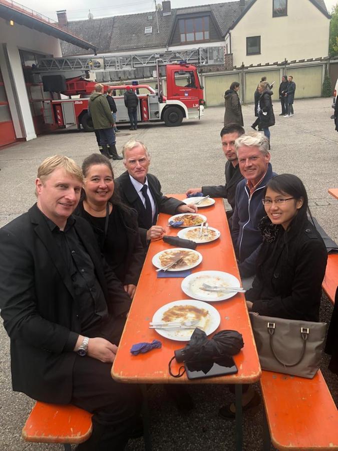 Auf dem Foto sitzt vorne links Stefan Massopust, hinter ihm seine Frau und gegenüber Mitarbeiterin Phuong Nguyen zusammen mit anderen Mitwirkenden. Nach diesen drei gilt es, Ausschau zu halten.