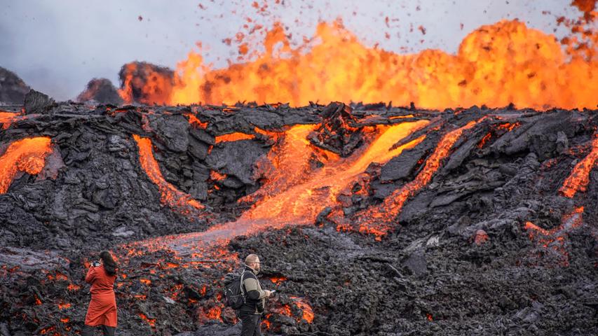Menschen betrachten Lava, die auf dem Vulkan Fagradalsfjall fließt. Auf Island hat ein erneuter Vulkanausbruch begonnen. Die erwartete Eruption habe in der Nähe des Bergs Fagradalsfjall auf der Reykjanes-Halbinsel südwestlich von Reykjavik begonnen, teilte die isländische Wetterbehörde am Mittwochnachmittag mit.