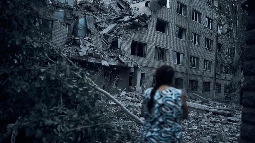 Ukraine, Mykolajiw: Eine Frau geht inmitten der Trümmer an einem Wohnhaus vorbei, das nach nächtlichem Beschuss zerstört worden ist.
