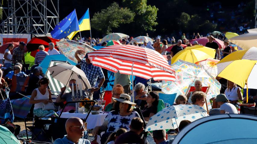 Besucher zeigen mit einer Europafahne und dem Blaugelb der Ukraine Flagge. 