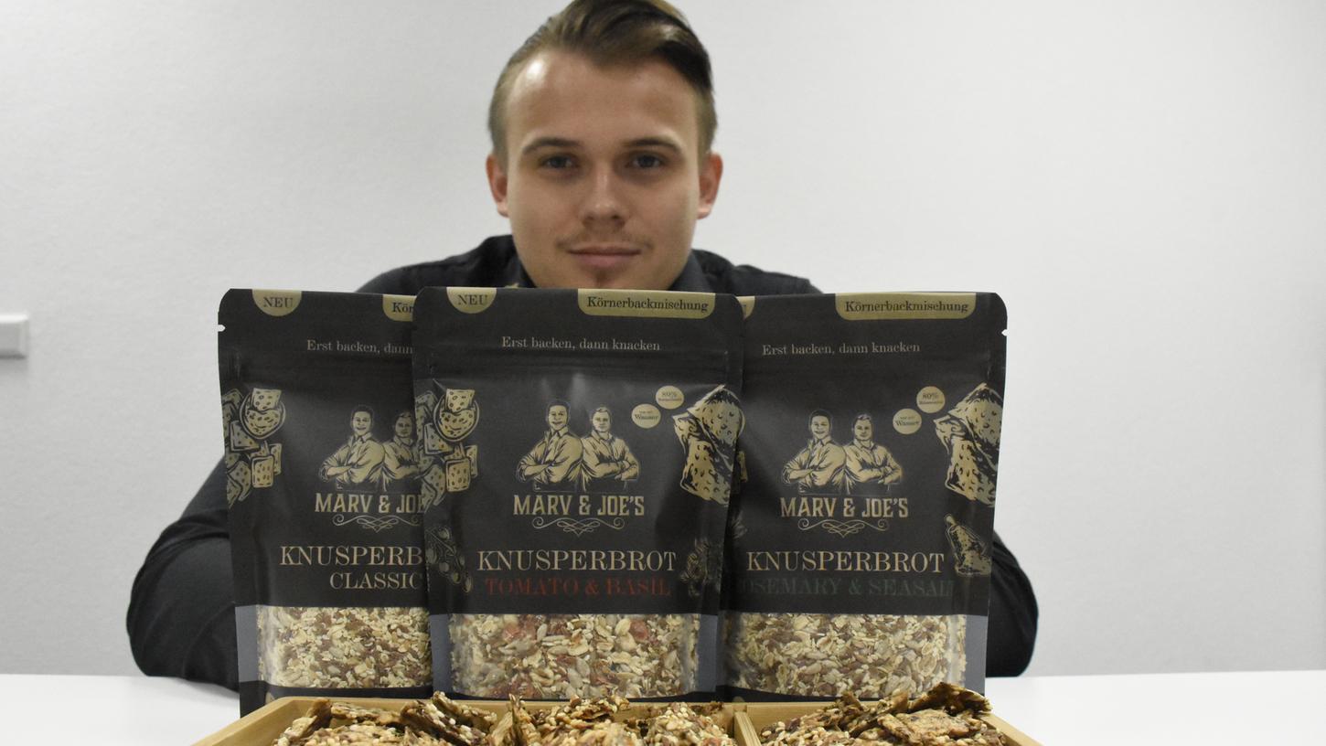 Hinten die Körnerbackmischung, vorne die fertigen Cracker. Jonathan Schürgers präsentiert das Produkt, das er und sein Kumpel Marvin Chennault verkaufen. Ihre Marke "Marv & Joe's" wird bereits in 20 Supermärkten in der Region angeboten. Hinten die Körnerbackmischung, vorne die fertigen Cracker. Jonathan Schürgers präsentiert das Produkt, das er und sein Kumpel Marvin Chennault verkaufen. Ihre Marke "Marv & Joe's" wird bereits in 20 Supermärkten in der Region angeboten.