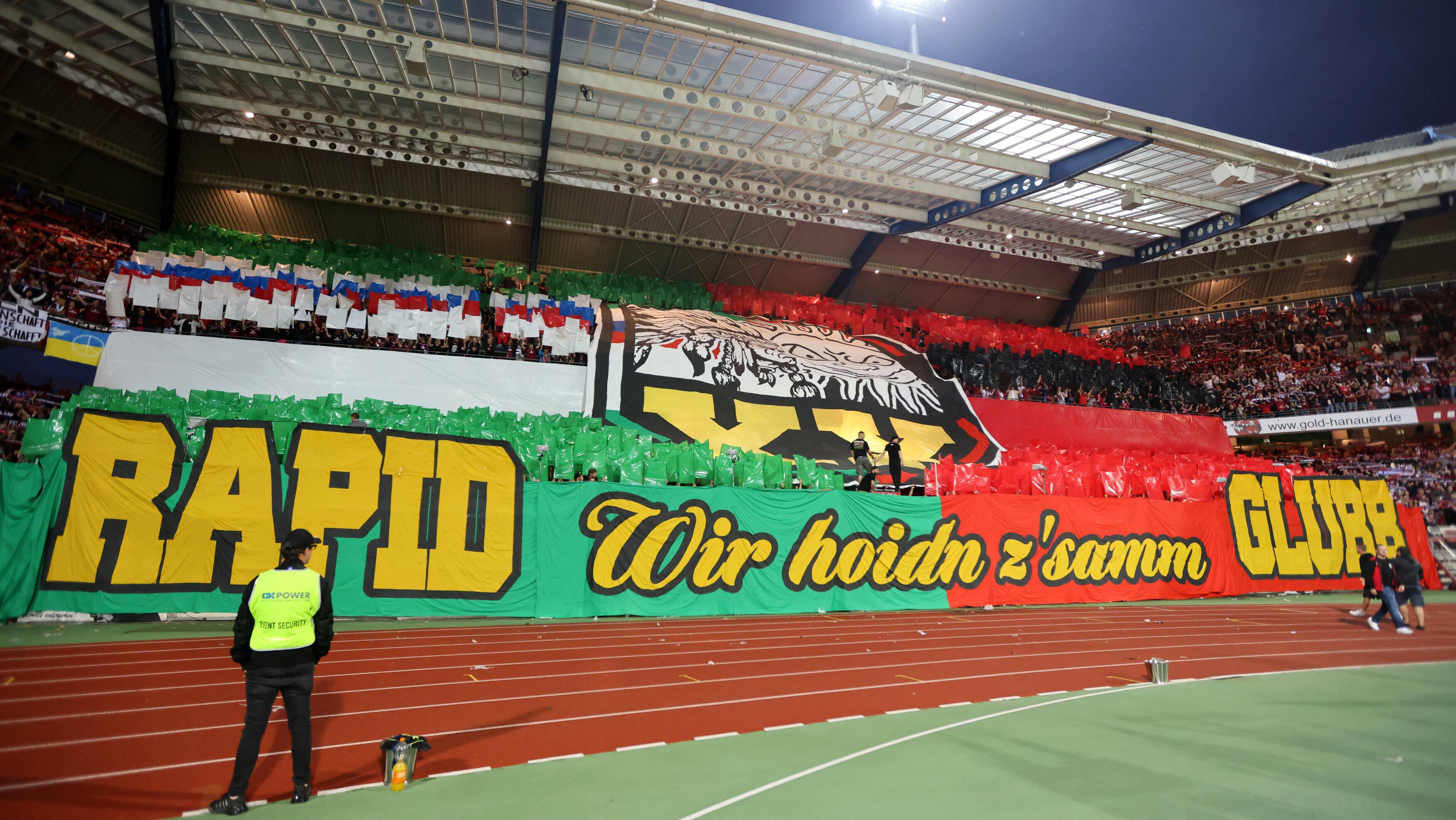 <p>Darunter ein neues Spruchband: "RAPID - Wir hoidn z’samm - GLUBB".</p>
