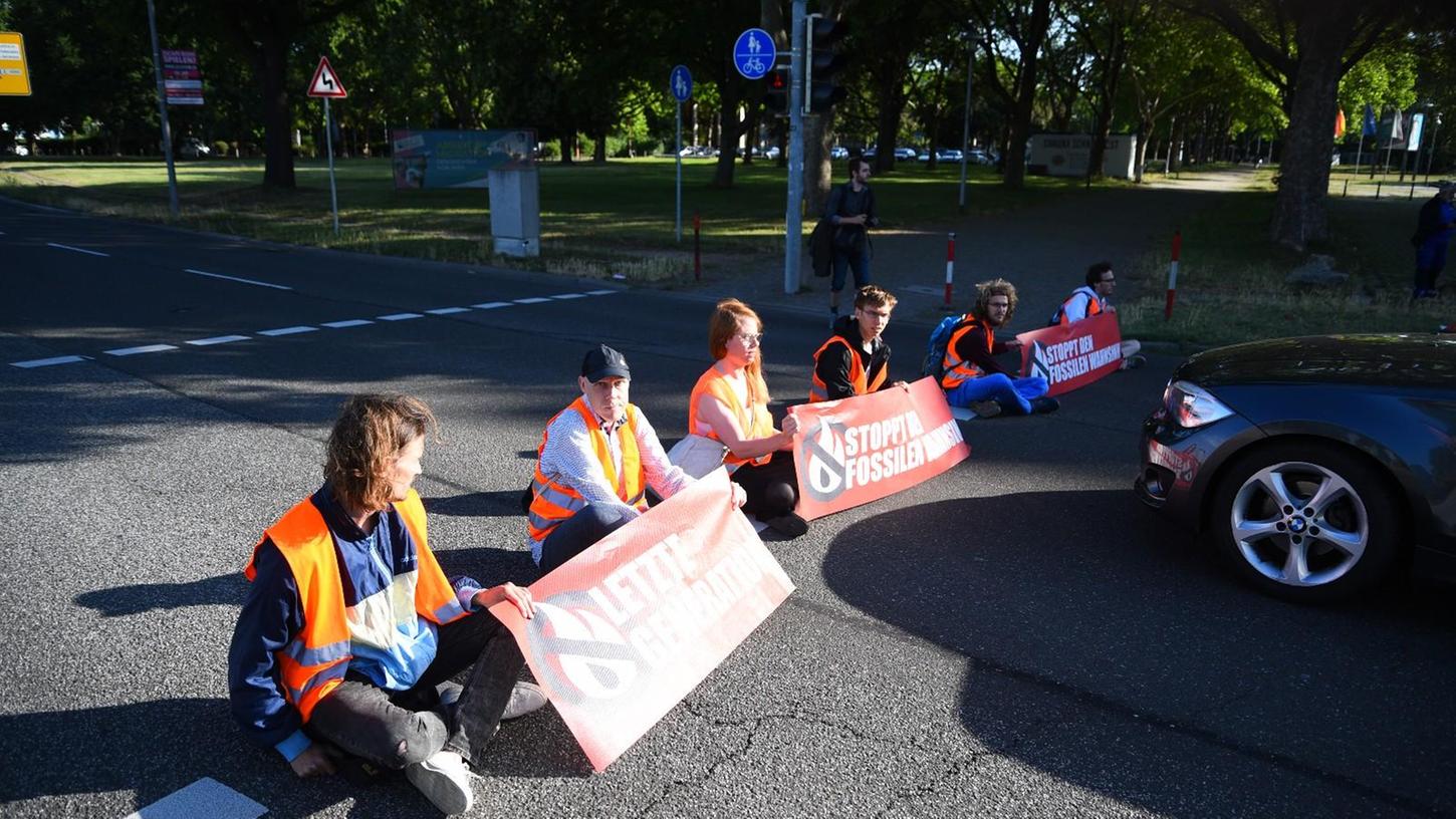 Aktivisten der Gruppe «Letzte Generation» sitzen bei einer Blockade auf einer Straße. 