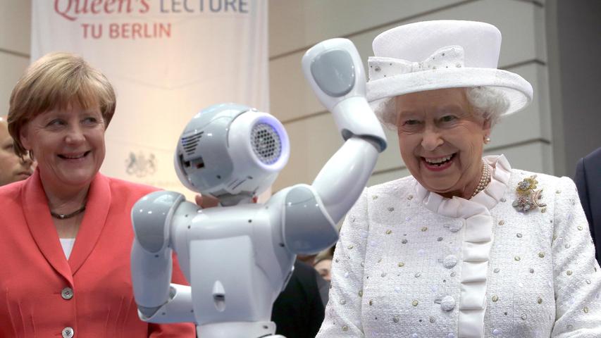 Zwei Damen, die Technik lieben und voranbringen: Queen Elizabeth und Angie Merkel freuen sich über einen kleinen humanoiden Roboter an der Technischen Uni Berlin.