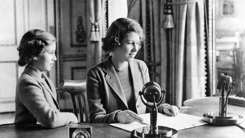 Prinzessin Elizabeth (r), damals 14 Jahre alt, und ihre Schwester Prinzessin Margaret sitzen nach der Rundfunk-Ansprache während der Radiosendung "Children's Hour" an einem Schreibtisch in Schloss Windsor. In einer Ansprache versicherte sie den britischen Soldaten im Zweiten Weltkrieg die Unterstützung der Kinder und Jugendlichen in der Heimat. 