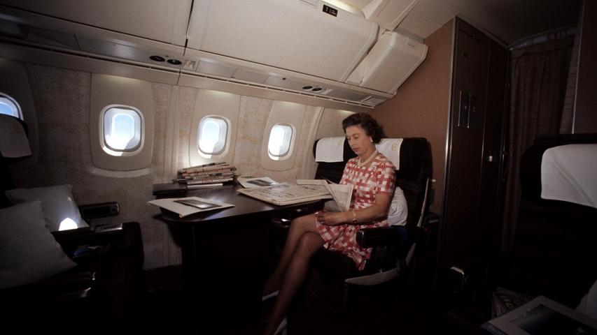 Königin Elizabeth II. beim Zeitungslesen während ihres Rückflugs von Bridgetown, Barbados, in der Überschallmaschine Concorde nach ihrer Tournee zum Silbernen Jubiläum durch Kanada und die Westindischen Inseln.