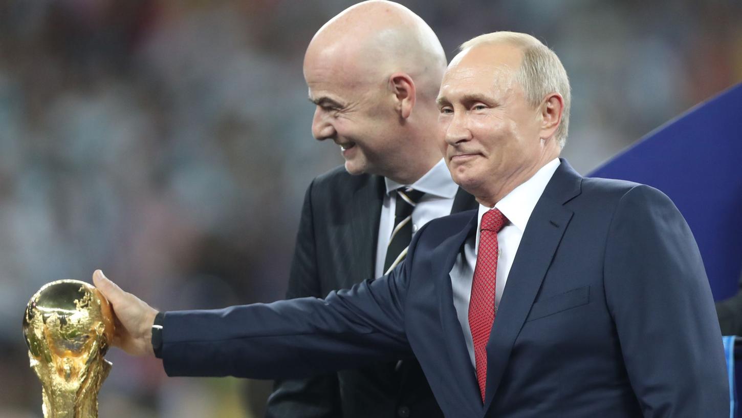 Die letzte WM 2018 richtete als Gastgeber Russland aus. Wladimir Putin steht neben FIFA-Präsident Gianni Infantino am WM-Pokal.