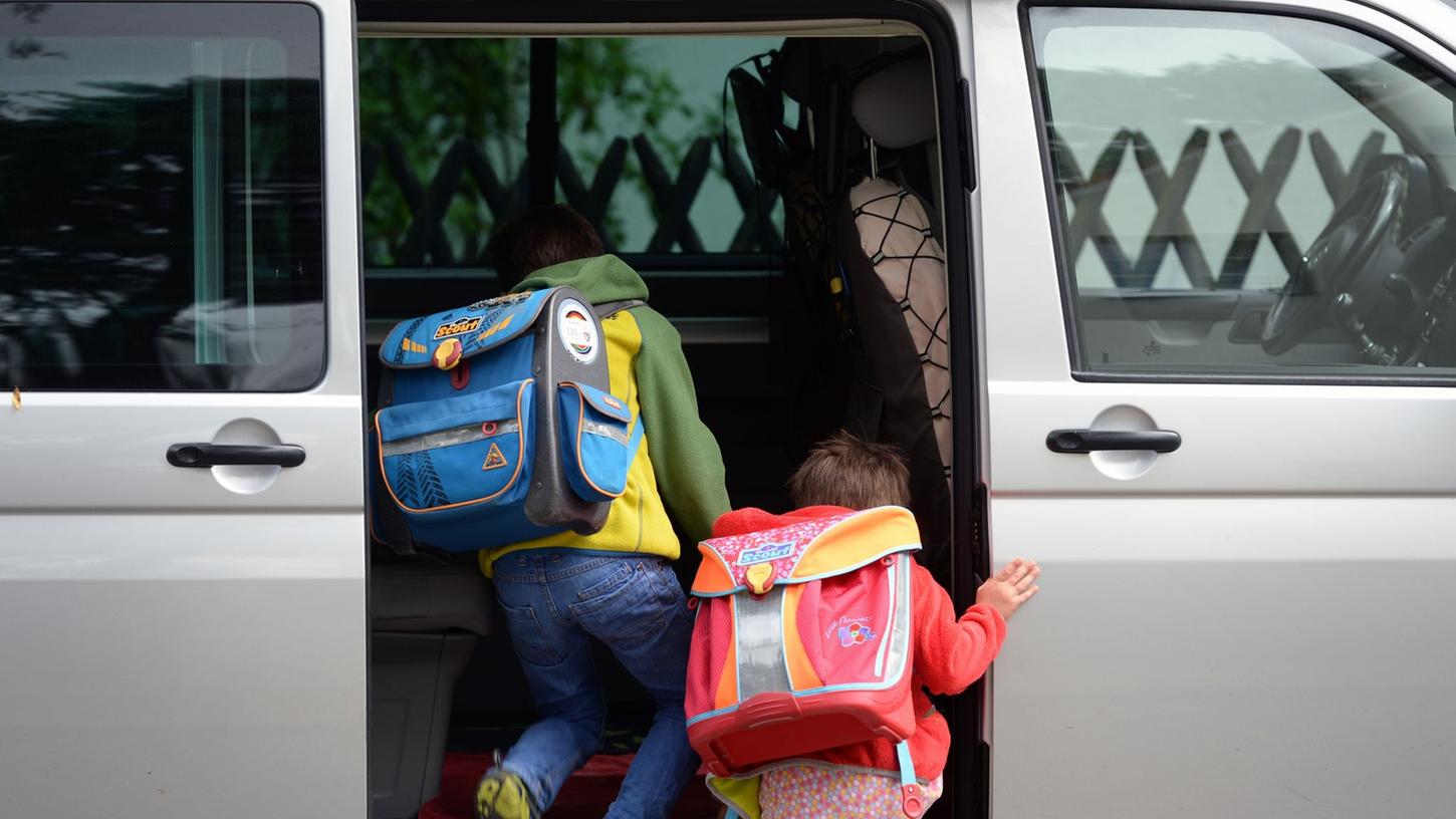 Schulkinder steigen in ein privates Fahrzeug. Elterntaxis verstopfen oft die Straßen vor den Schulen. Schulkinder steigen in ein privates Fahrzeug. Elterntaxis verstopfen oft die Straßen vor den Schulen.