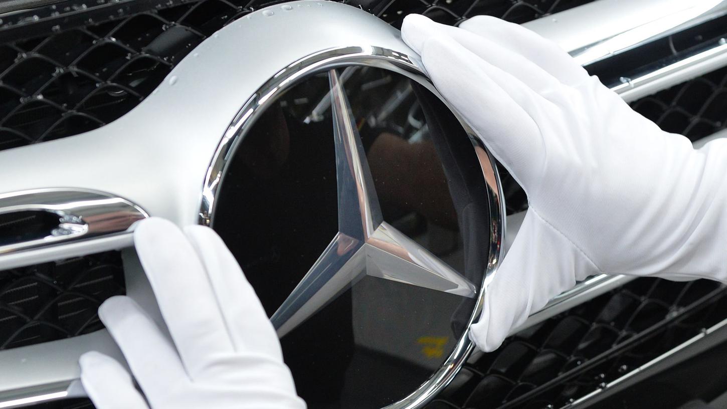Ein Mitarbeiter von Mercedes-Benz bringt im Werk in Bremen den Stern an einem C-Klasse Modell an.