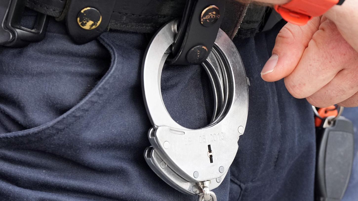 Handfesseln aus Metall hängen am Gürtel eines Polizisten. Handfesseln aus Metall hängen am Gürtel eines Polizisten.