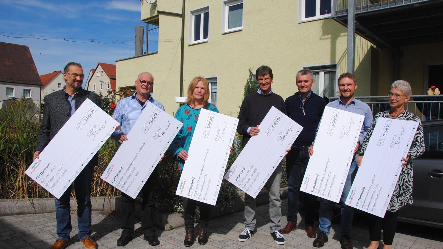 Scheckübergabe in Forchheim (v.l.): Martin Burda, Puckenhof e.V. Erlangen, Dietrich Färber, Elterninitiative krebskranker Kinder Erlangen, Flora Heinlein, Hospizverein Forchheim, Oliver Flotow, Bürgerstiftung Erlangen, Christian Reckziegel, Siemens Healthineers, Peter Pfann, Lebenshilfe Forchheim und Susanne Opel, Hainbrunnenschule Forchheim.