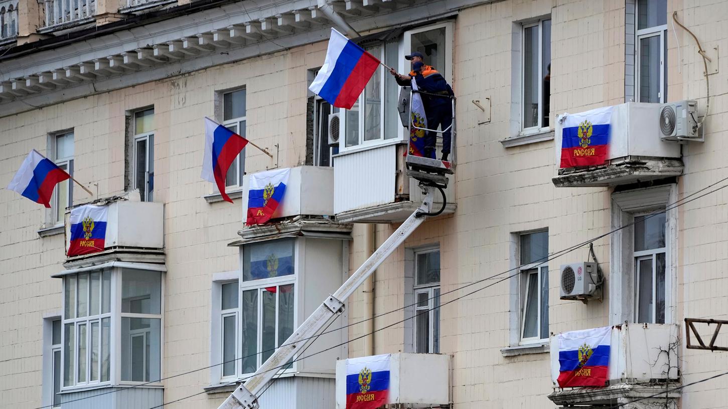Arbeiter hängen russische Fahnen an einem Wohnhaus in der von Russland unterstützten und von Separatisten kontrollierten Volksrepublik Luhansk auf. In den russisch-besetzten Gebieten der Ukraine fanden bis zum Dienstag international als Völkerrechtsbruch kritisierte Abstimmungen über einen Beitritt zu Russland statt.
Arbeiter hängen russische Fahnen an einem Wohnhaus in der von Russland unterstützten und von Separatisten kontrollierten Volksrepublik Luhansk auf. In den russisch-besetzten Gebieten der Ukraine fanden bis zum Dienstag international als Völkerrechtsbruch kritisierte Abstimmungen über einen Beitritt zu Russland statt.