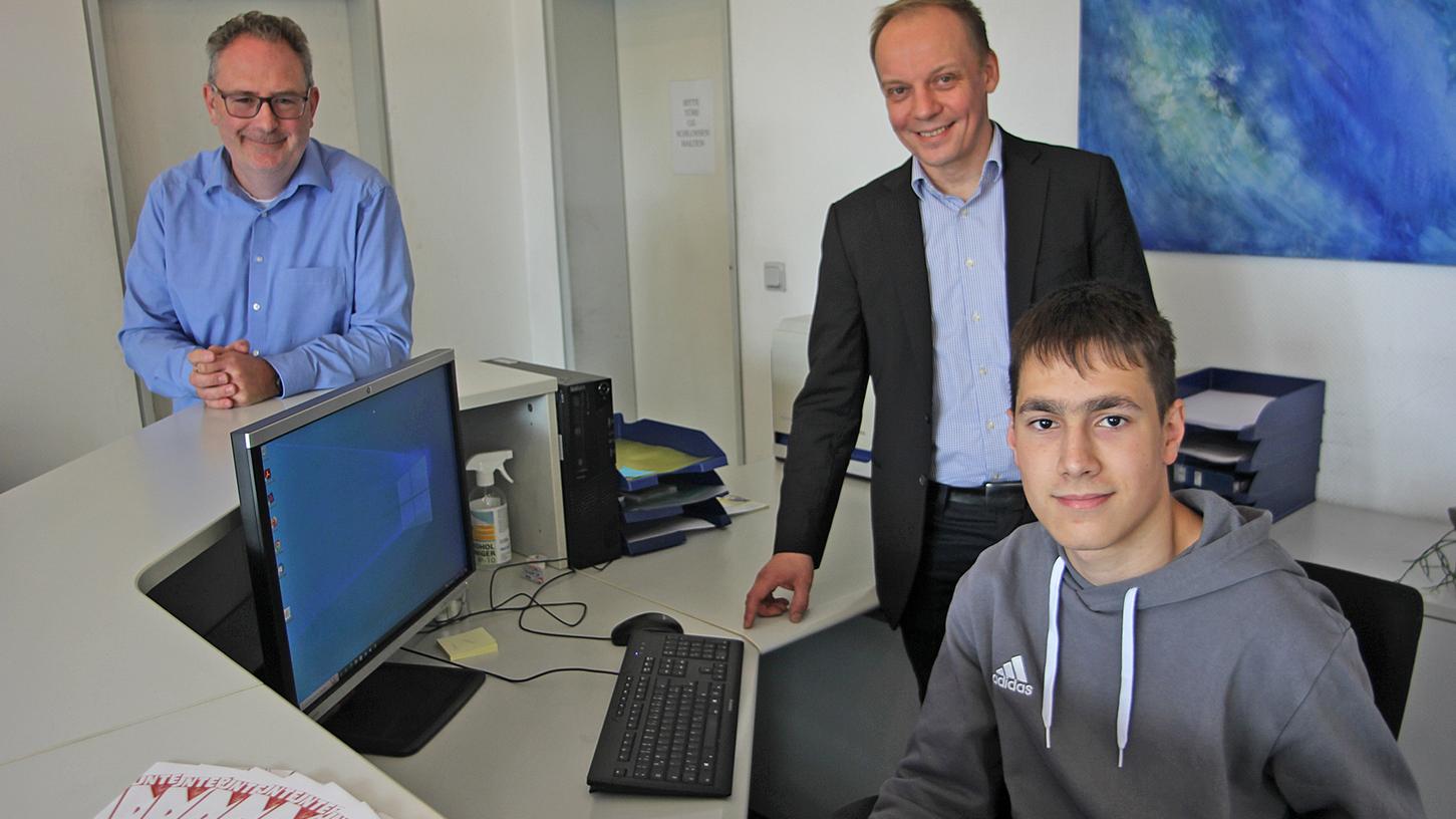Adrian Rogulj an seinem Arbeitsplatz am Empfang der Firma Reicolor in Ludersheim, in der Mitte Geschäftsführer Jürgen Reitenspiess, links Andreas Bräuer, Mitglied der Geschäftsleitung.