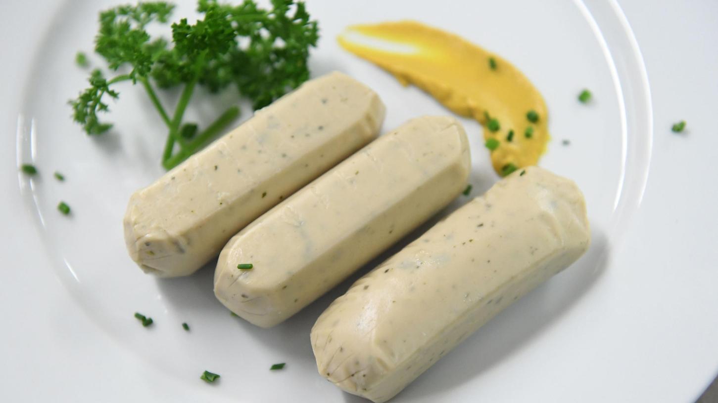 Vegane Weißwürste liegen auf einem Teller an der Essensausgabe im Hofbräuzelt auf dem Oktoberfest 2022.