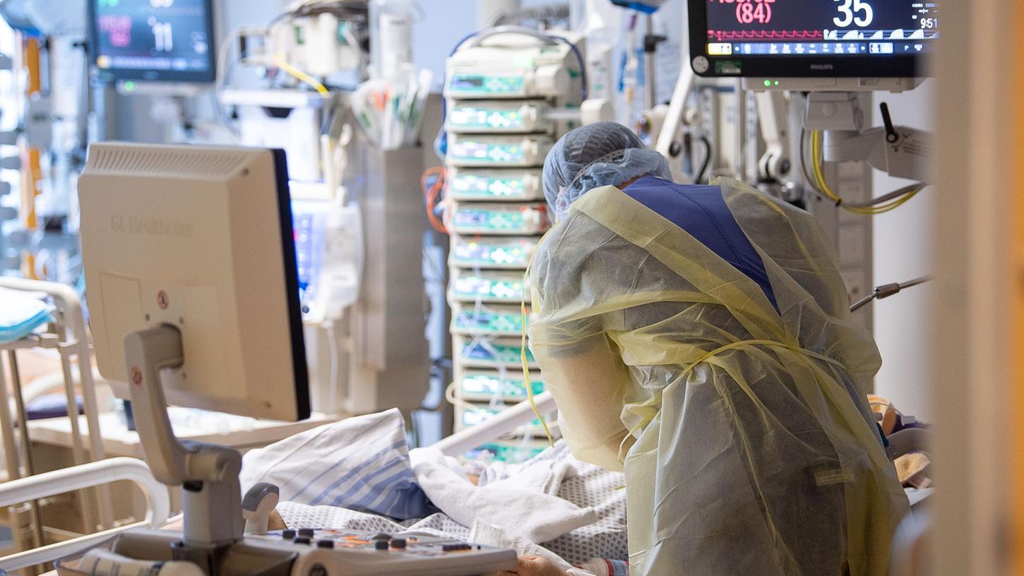 Ein Intensivpfleger steht auf der Intensivstation eines Krankenhauses neben einem Covid-19-Patienten. Ein Intensivpfleger steht auf der Intensivstation eines Krankenhauses neben einem Covid-19-Patienten.