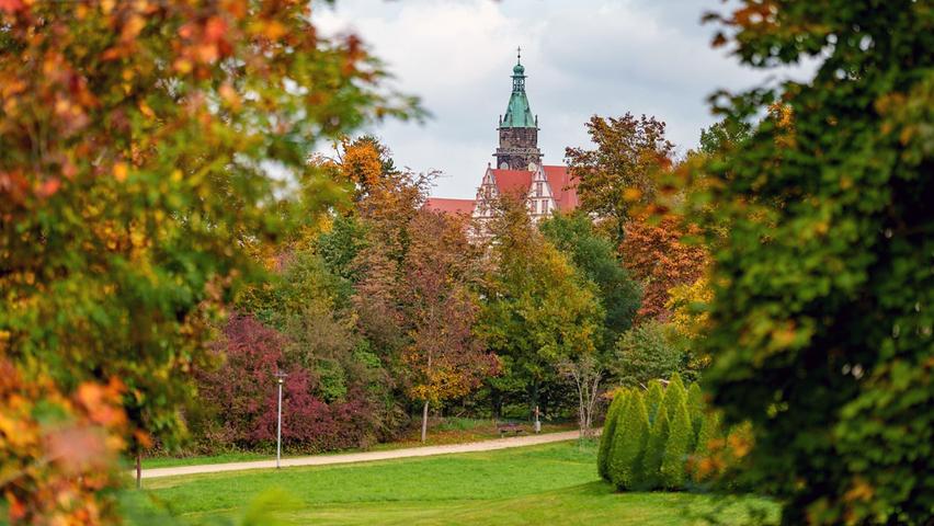 Rother Schloss und Stadtkirche auf einen Blick, umrahmt von buntem Herbstlaub.