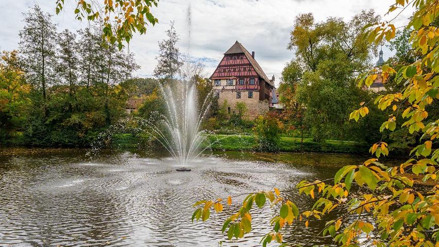 Eingerahmt von Wasser und Herbstlaub: Das Jahrsdorferhaus in Hilpoltstein im Herbstgewand.  