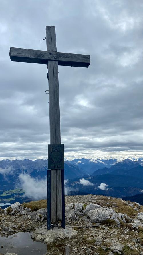 Im Hintergrund das Karwendelgebirge, im Vordergrund das Gipfelkreuz des Krottenkopfes. 